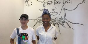 Teens posing in front of a mural in progress