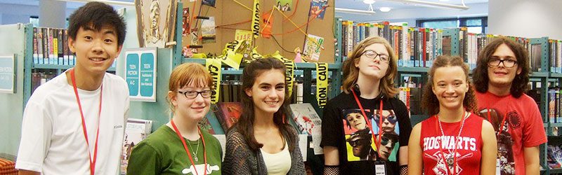 Group of teen volunteers in front of book display