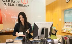 Library Assistant checks in books at the front desk of the Main Library