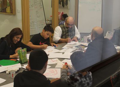 Adults and children around library conference room table