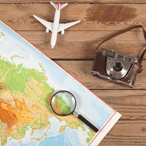 Map with magnifying glass, camera, and airplane