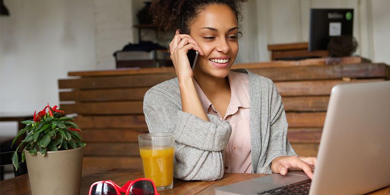 Woman on cell phone using computer