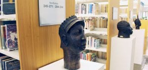 Sculptures on pedestals in front of bookshelves