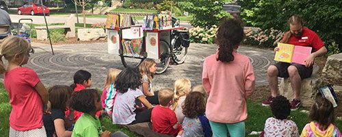 Children listening to a storytime from the Book Bike in the park