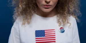 Person holding American flag and wearing vote button