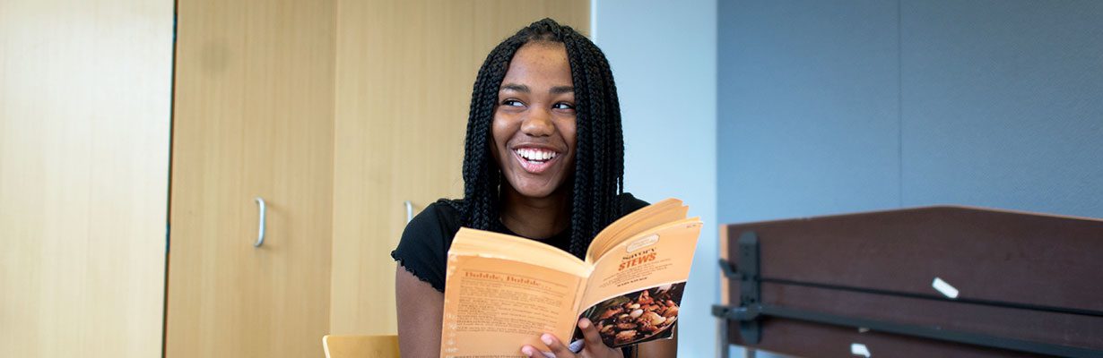 Teen holding book and laughing