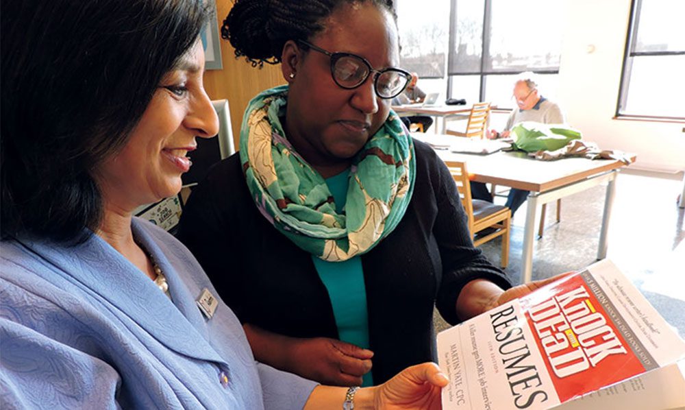 Two women looking at a resume book