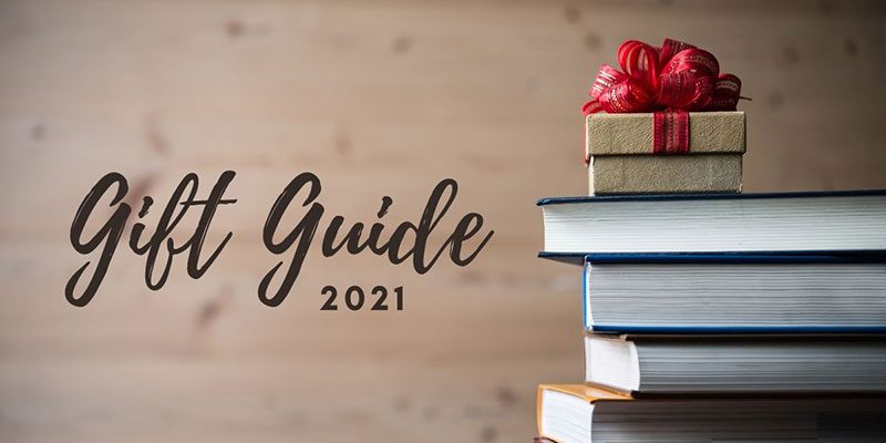 Gift Guide 2021 written on the left with a wrapped gift box sitting on top of a stack of books on the right