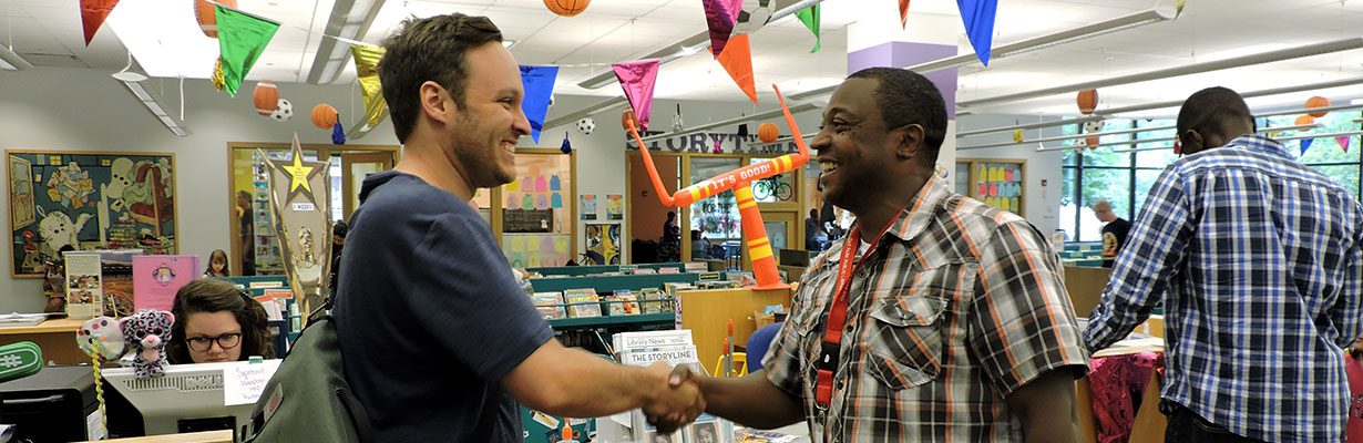 Rob Simmons shaking hands with a patron in the Main Library Children's Area