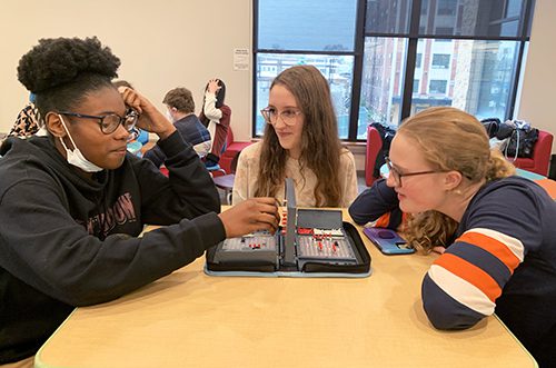 Three teenagers playing game on a table