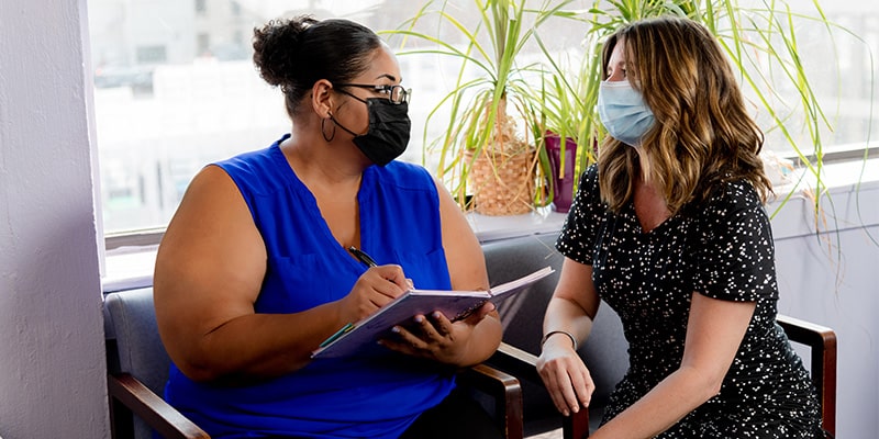 Patient and friend in clinic waiting room signing patient journal