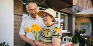 Older couple holding flowers and smiling at one another