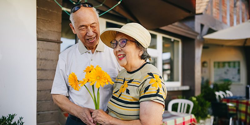 Older couple holding flowers and smiling at one another