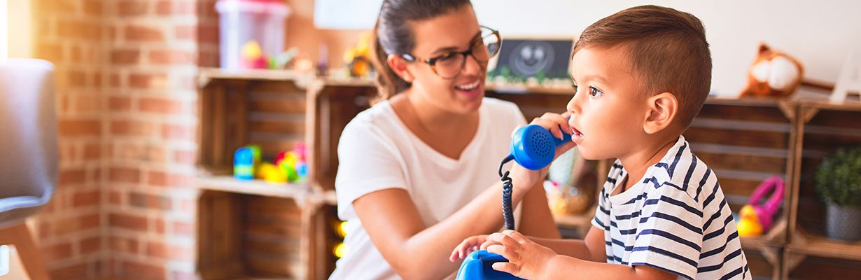 Caregiver with toddler listening to toy phone