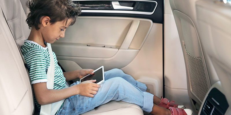 Kid using tablet in backseat of car