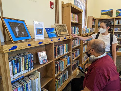 Vanley Roebuck looks at his artwork with Librarian Rose Barnes