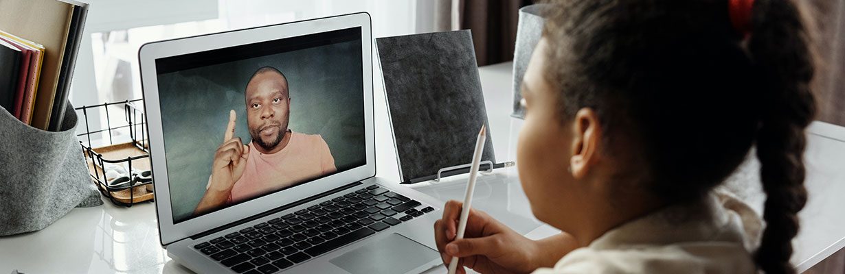 Student watching teacher on laptop