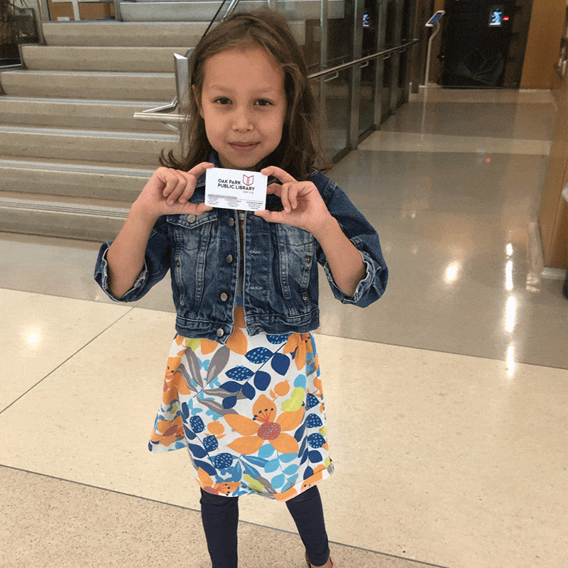 Child shows off library card with both hands