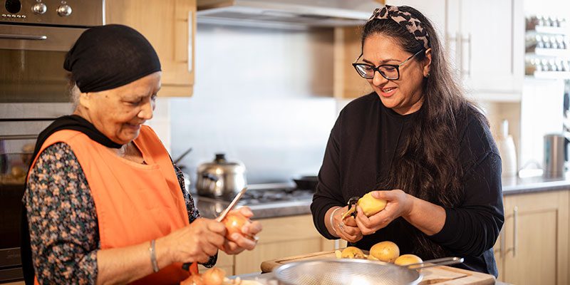 A mother and daughter cutting up food and preparing a meal together