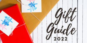 Gift Guide 2022 text next to two wrapped boxes with cards featuring stamped trees