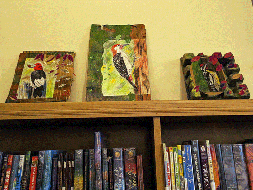 Artwork showing a red-headed woodpecker, a red-bellied woodpecker, and a yellow-bellied sapsucker above the bookshelves at Maze Branch