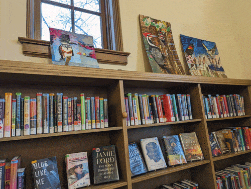 Art showing a belted kingfisher, pileated woodpeckers, and red-winged blackbirds above bookshelves at Maze Branch