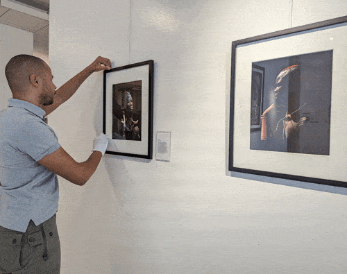 Photographer Jason Dorsey aligns a framed portrait in his exhibit Alkebulan Shadows.