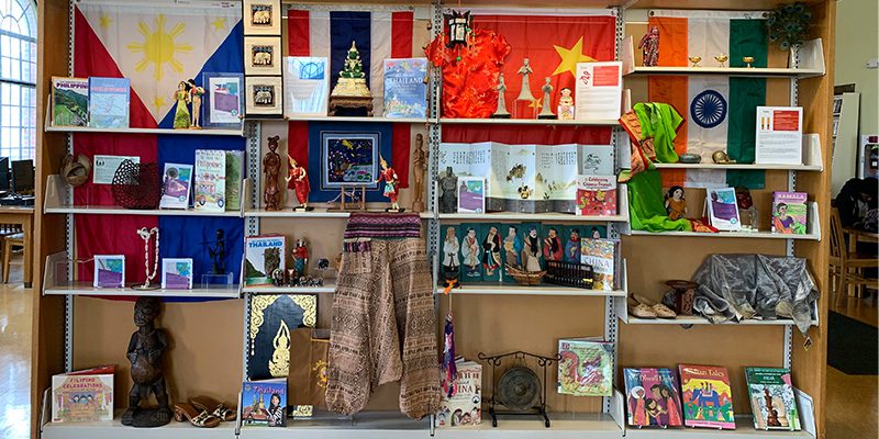Library shelves full of textiles, paintings, statues, and books celebrating Asian American and Pacific Islander heritage.