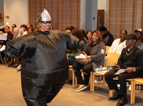 Library staff member models a costume based on that worn by Missy Elliot in "The Rain (Supa Dupa Fly)" in the hip hop fashion show 