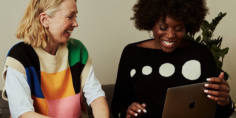 Two people laughing while looking at a laptop