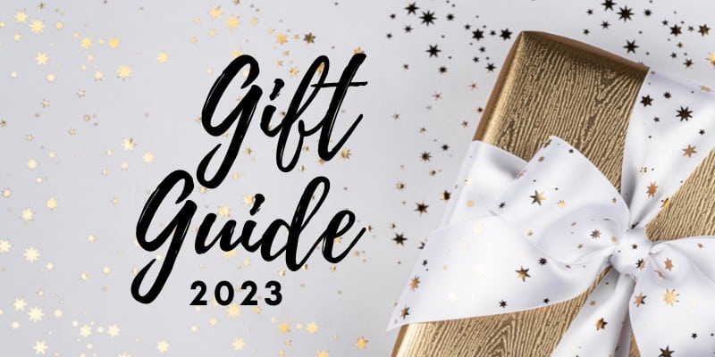 Gift Guide 2023 text with a gold gift box wrapped in a white ribbon surrounded by glitter stars