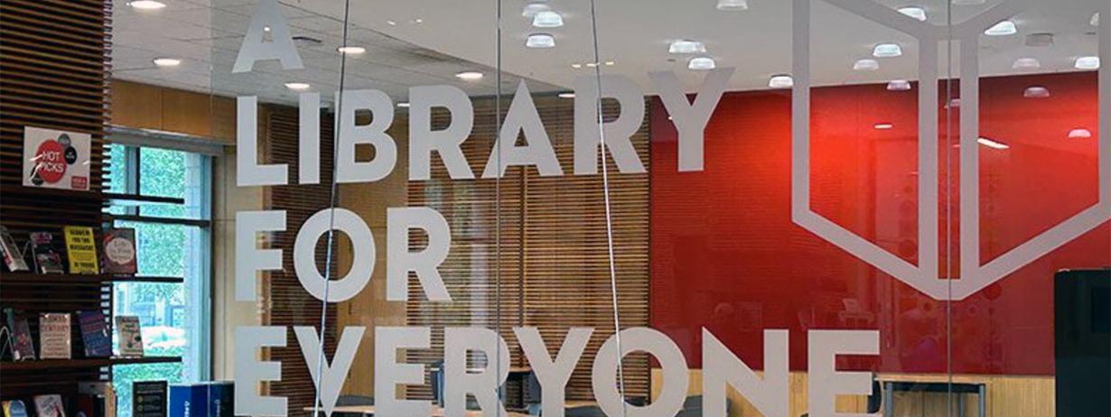 Glass wall in Main Library Lobby that reads in frosted letters "A Library for Everyone"