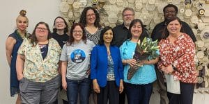 Group of library staff pose together against an artwork backdrop