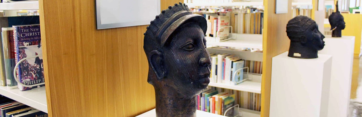 Three replica Benin bronzes on display in the library stacks