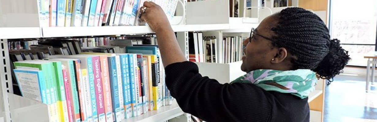 Person reaching for a library book on the shelf