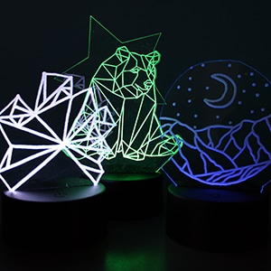 Three LED lamps: a geometric starburst, a bear, and a mountain scene with a moon in the sky