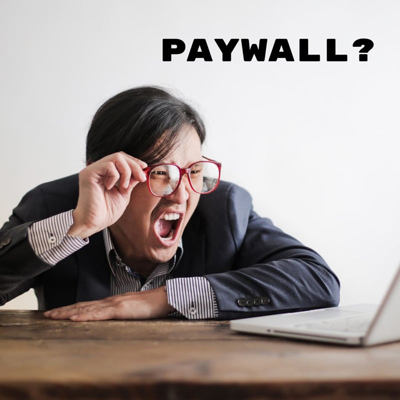 Woman peers through glasses at laptop, looking shocked and angry. Text on photo says "Paywall?"