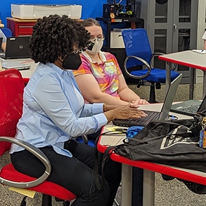 Two people work at a laptop
