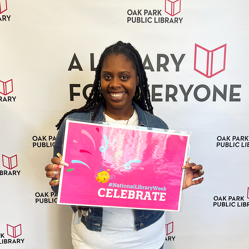 Library staff member holding a sign that reads, #NationalLibraryWeek Celebrate