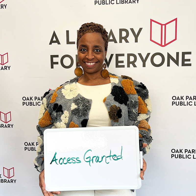 Library staff member holding a sign that reads, Access Granted