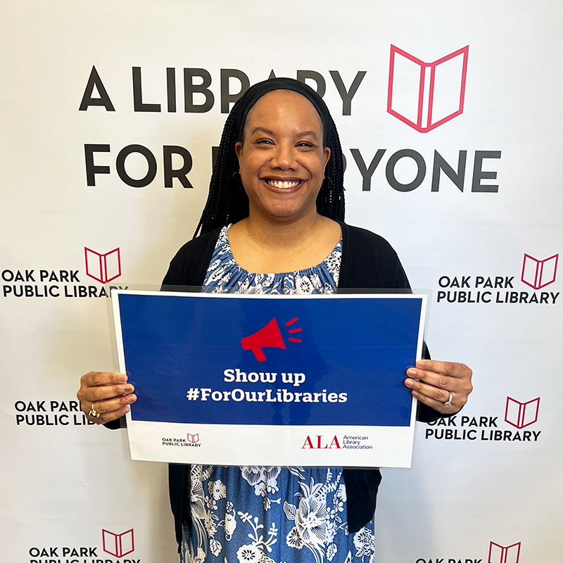 Library staff member holding a sign that reads, Show up #ForOurLibraries