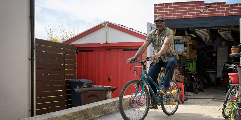 Older adult riding a bicycle in front of an open garage