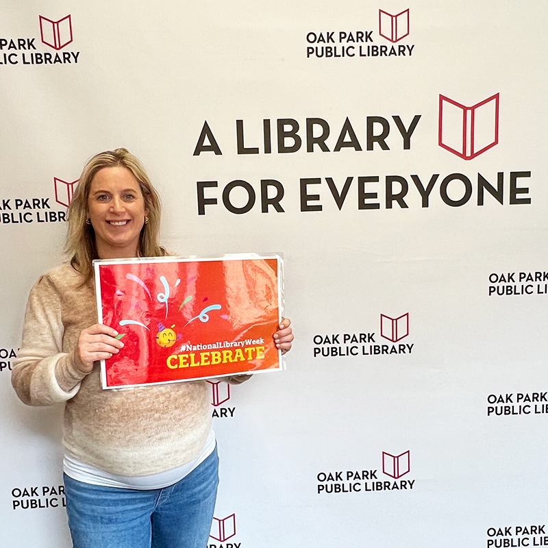 Library staff member holding a sign that reads, #NationalLibraryWeek Celebrate