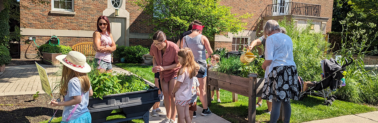 Adults and children exploring the raised garden beds outside Maze Branch