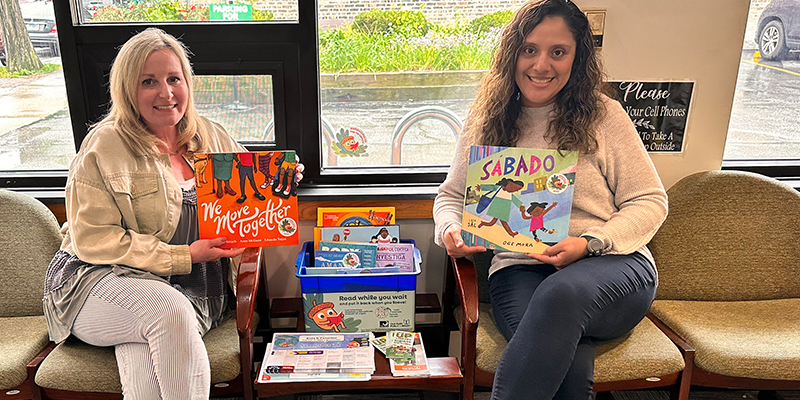 ownship staff members Stephanie Scaletta (Marketing and Communications Manager) and Yazmin Morales (Programs and Engagement Manager) hold up books in the Oak Park Township lobby.