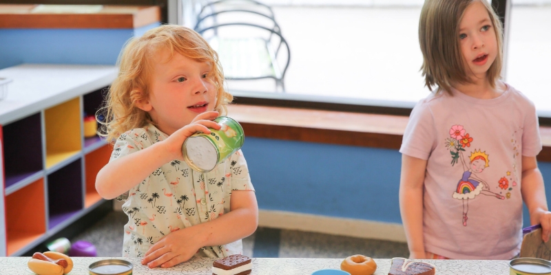 Kids play with pretend food in a pretend kitchen.