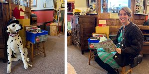 Interior of Oak Park River Forest Museum. A stuffed Dalmation wearing a firefighter's hat sits next to a bin of books, and a person sits on a stool with a picture book.