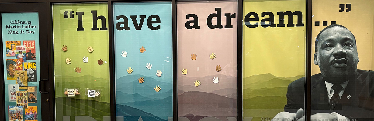 Window display with Martin Luther King Jr. photograph, words I have a dream, book covers images, and paper hands.