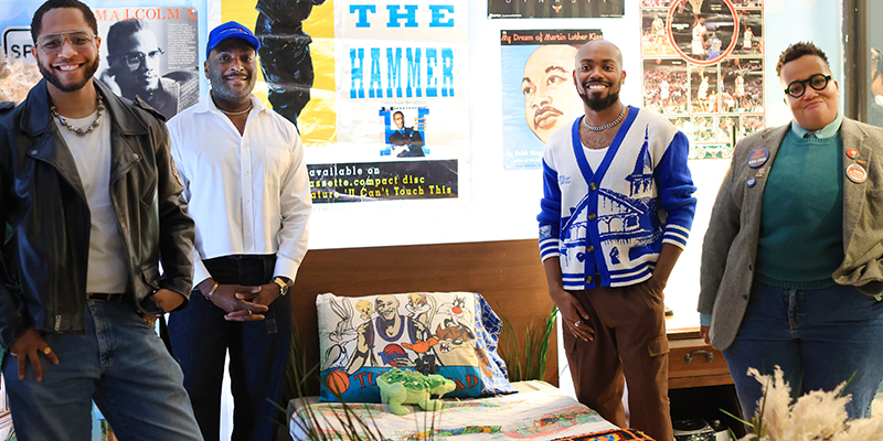 Four people stand in a recreated childhood bedroom.