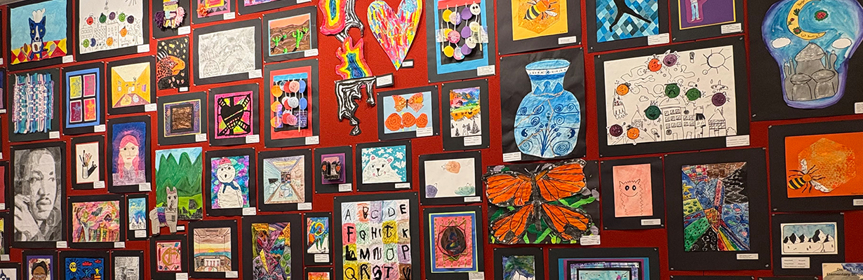 Gallery wall of colorful artwork by children.